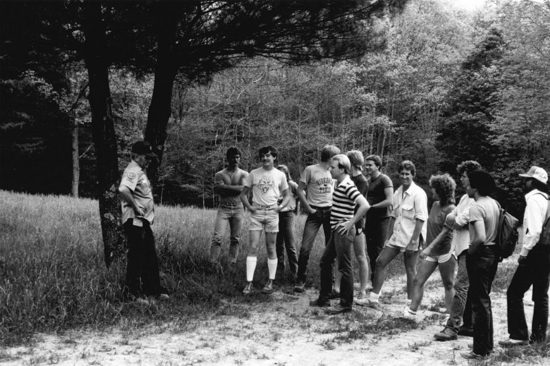 Students gathered around an instructor next to a tree