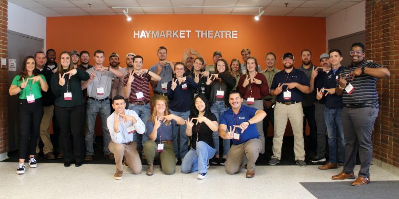 CNRE alumni posing in front of Haymarket Theatre throwing the VT hand sign