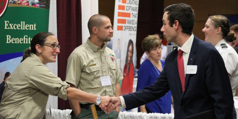 Student shaking hands with a career fair presenter.