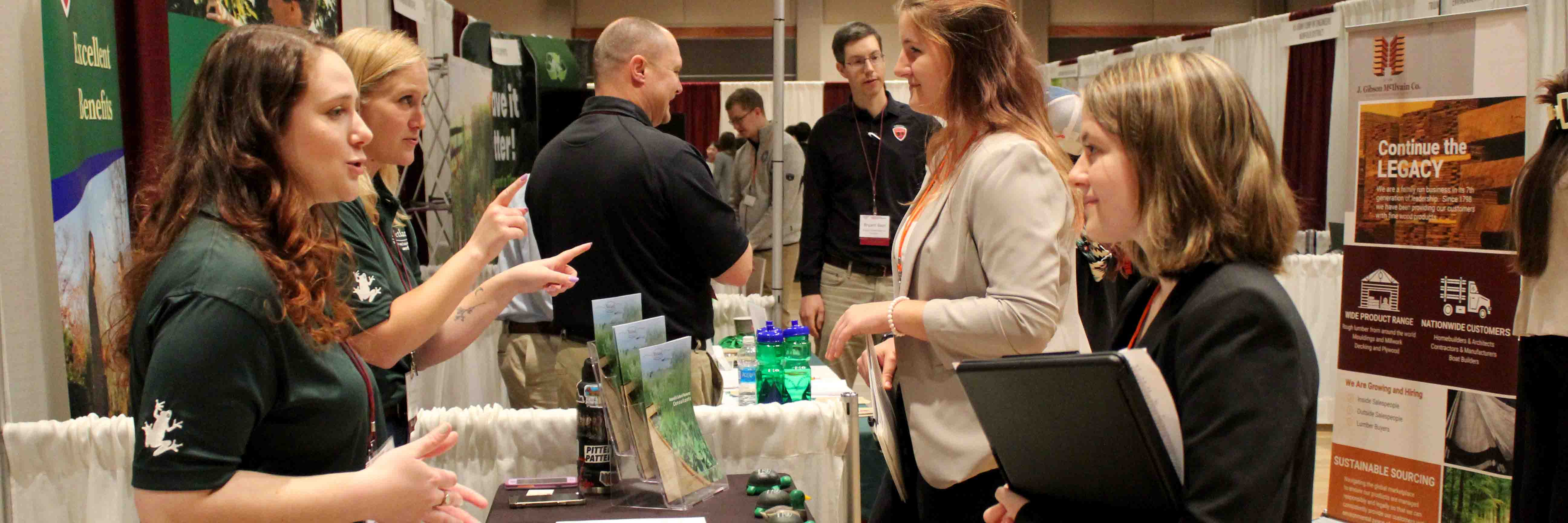 Employers talking to students at a career fair booth