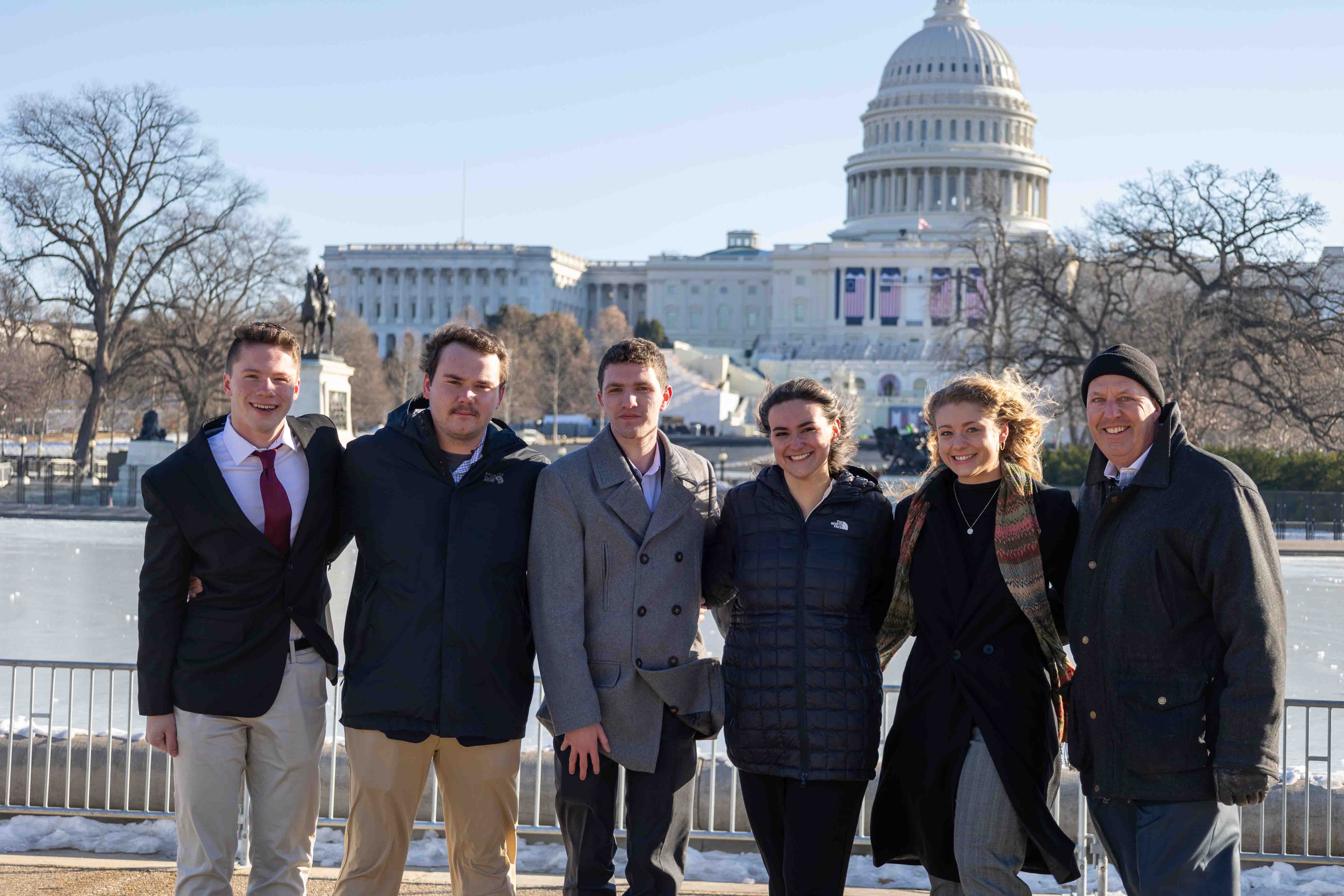 Six people posed in front of the United States Capitol