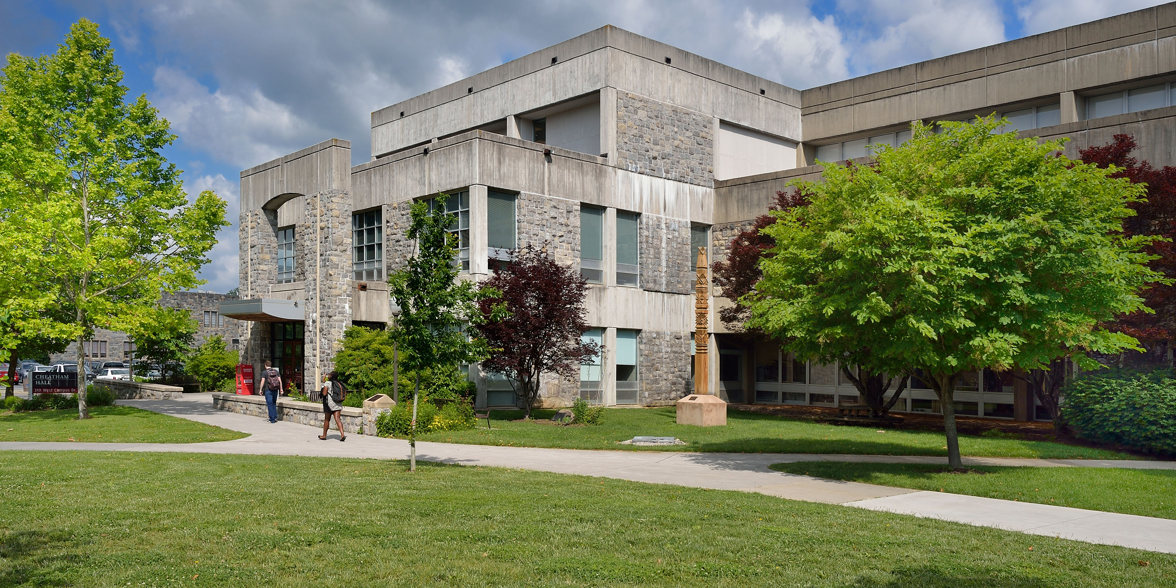 Students on a concrete path walking towards a building made of Hokie stone.