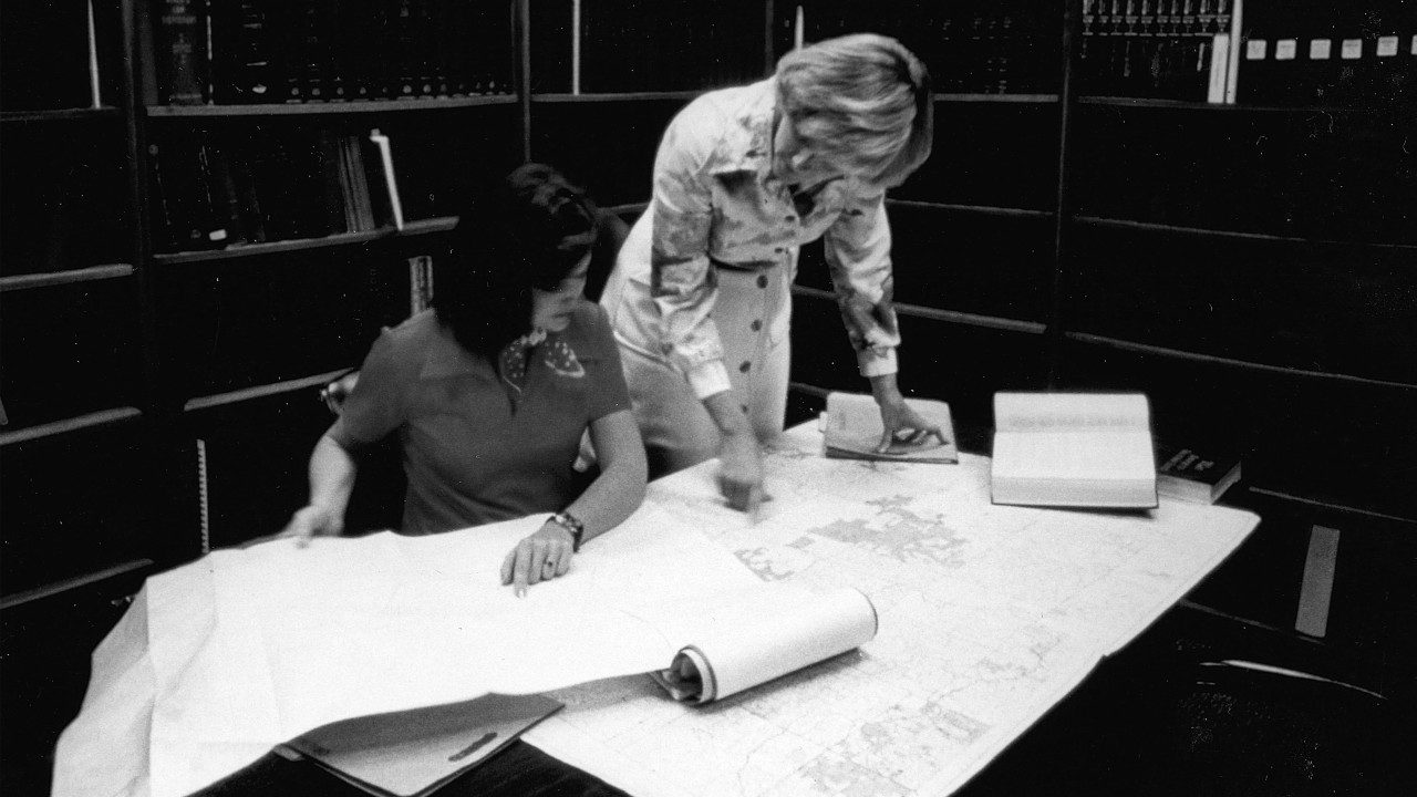 Two female students looking at maps laid out on a table