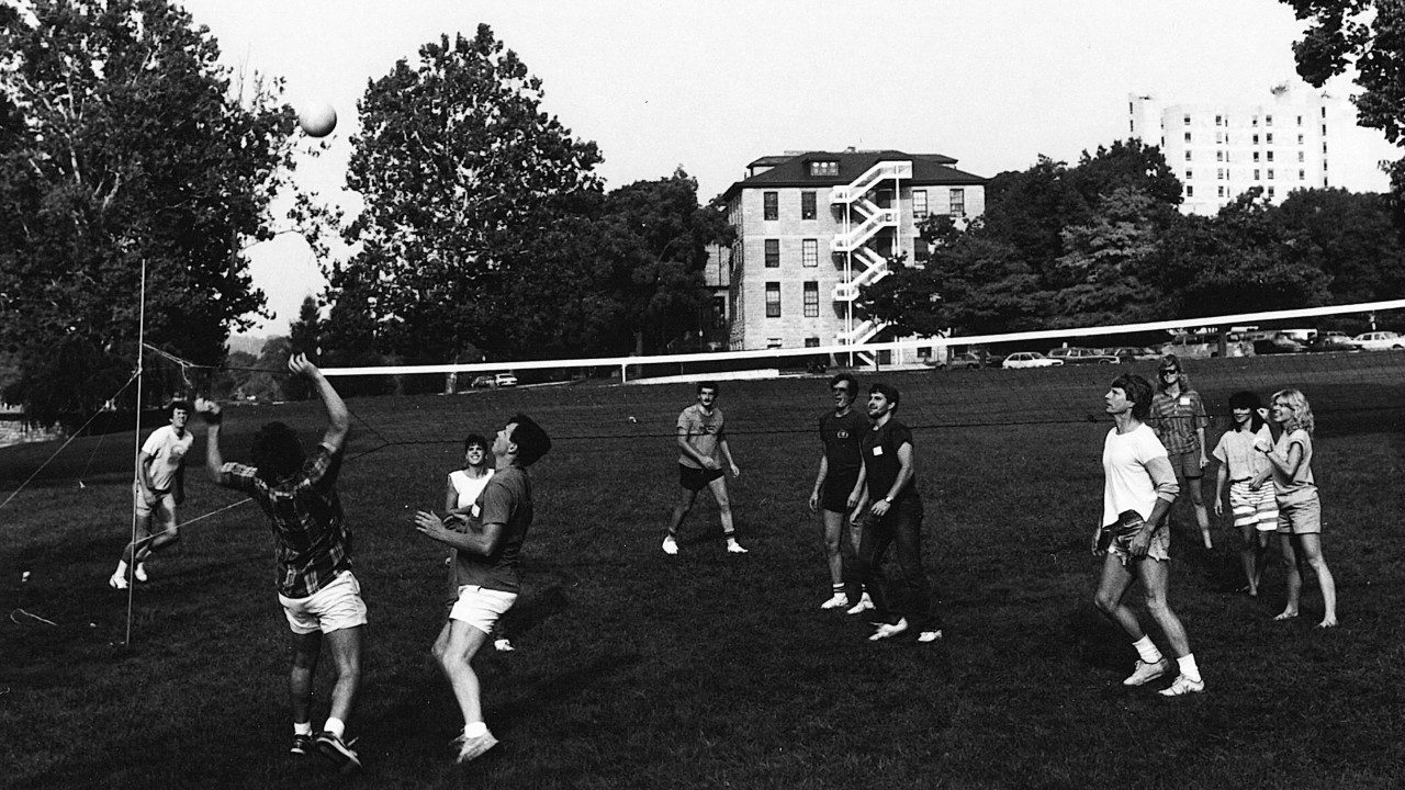 Students in a grass field playing volleyball