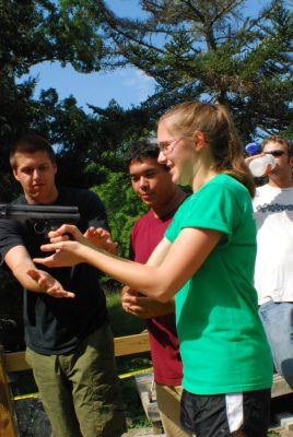 Kara Kosarski (R) tries her hand at using a dart pistol, which is used to chemically immobilize mammals. Assisting her her student Robert Nave (L) and Vance Nepomuceno, a course veteran who volunteered to help with the field experience.