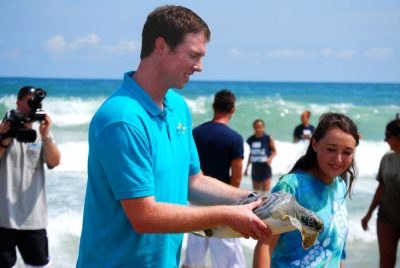 Clark and a fellow “Aqua Kids” cast member release a rehabilitated green sea turtle on Topsail Beach in North Carolina.