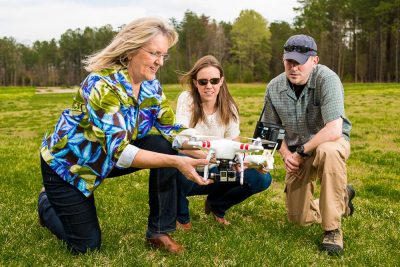 Cherie Aukland (left), head of the GIS program at Thomas Nelson Community College, and two students examine a DJI Phantom 2 aircraft. Aukland is one of several partners who assist Professor John McGee in developing the UAS education program for community colleges across the state.