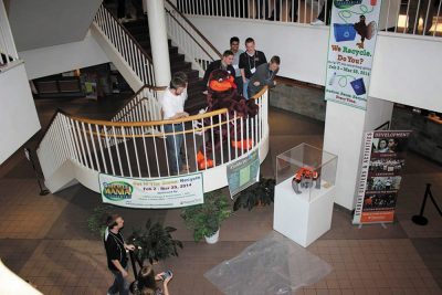 Hokie Bird with students performing an egg drop at the top of stairs