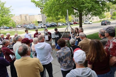 A group of people stand around a weather station composed of metal poles and instruments. 