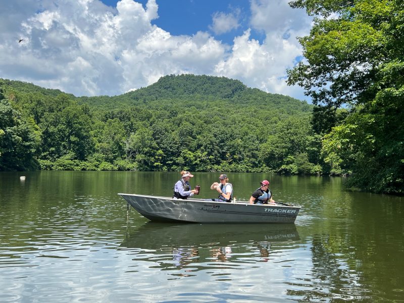 This photo shows three people in a small boat collecting water samples from the lake.